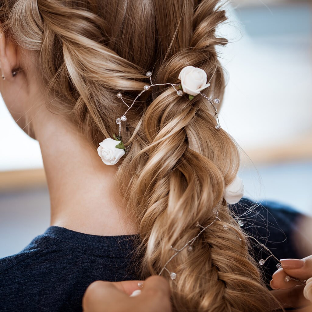 Female hairdresser making hairstyle to beautiful blonde girl in beauty salon. Copy space.